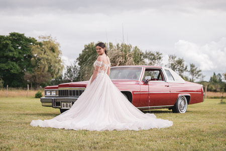 Photo de la mariée en robe devant une vieille voiture rouge