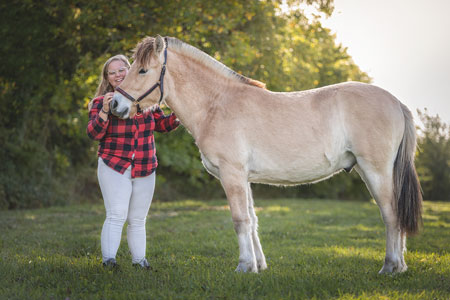 cavalière a côté de son cheval fjord dans un pré