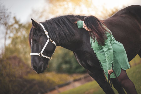 Cavalière en robe verte sur son cheval arabe dans un champ de colza