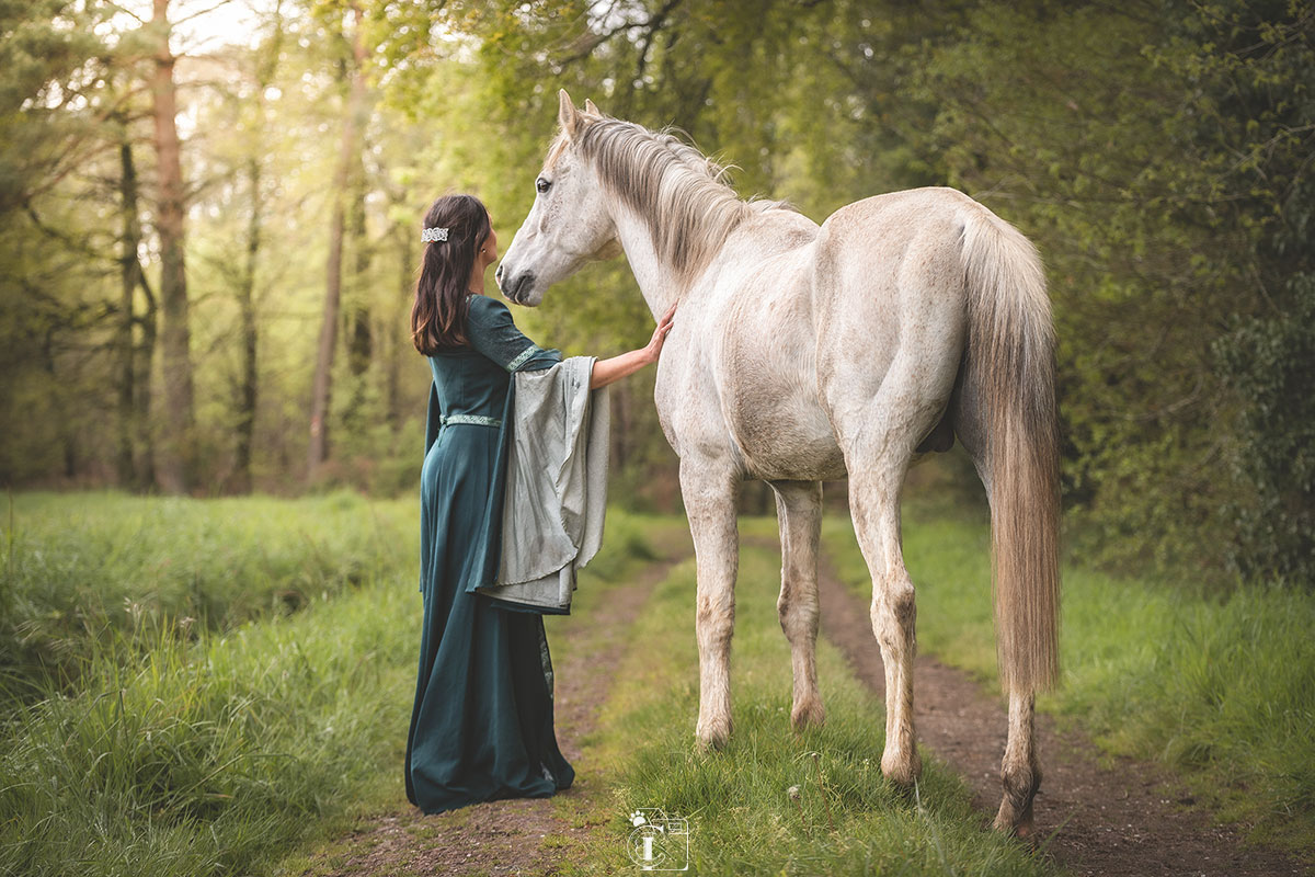 Cavalière sur son cheval arabe et avec son cacatoès sur l'épaule sous un arbre