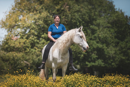 La propriétaire est assis à cru sur son cheval gris au milieu de boutons d'or