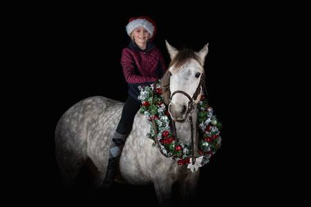 cavalière sur un cheval avec une guirlande de noël sur fond noir